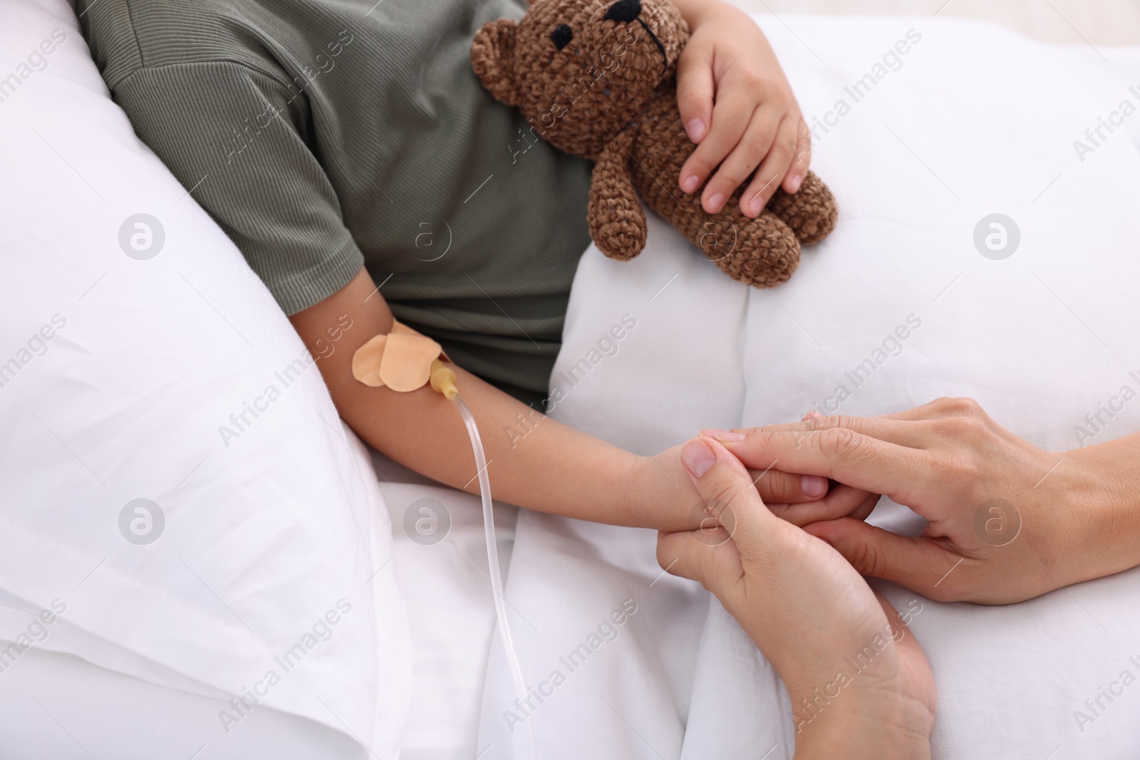 Photo of Doctor examining little girl on bed at hospital, closeup