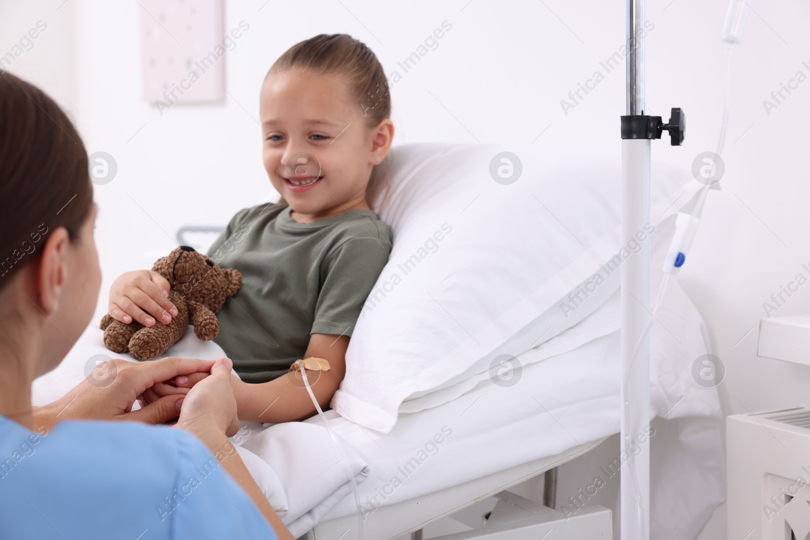 Photo of Doctor examining little girl on bed at hospital