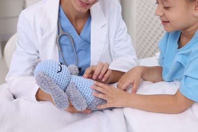 Photo of Doctor examining little girl on bed at hospital, closeup