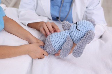 Photo of Doctor examining little girl on bed at hospital, closeup