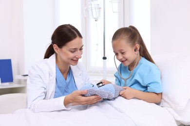 Photo of Doctor examining little girl on bed at hospital