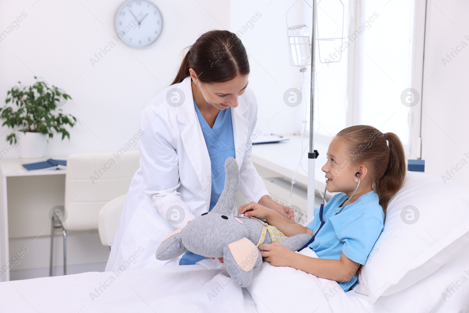 Photo of Doctor examining little girl on bed at hospital