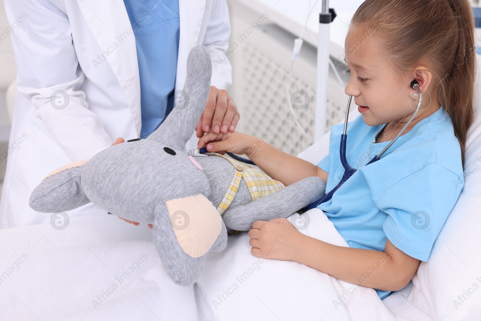 Photo of Doctor examining little girl on bed at hospital, closeup