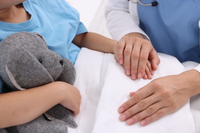 Photo of Doctor examining little girl on bed at hospital, closeup