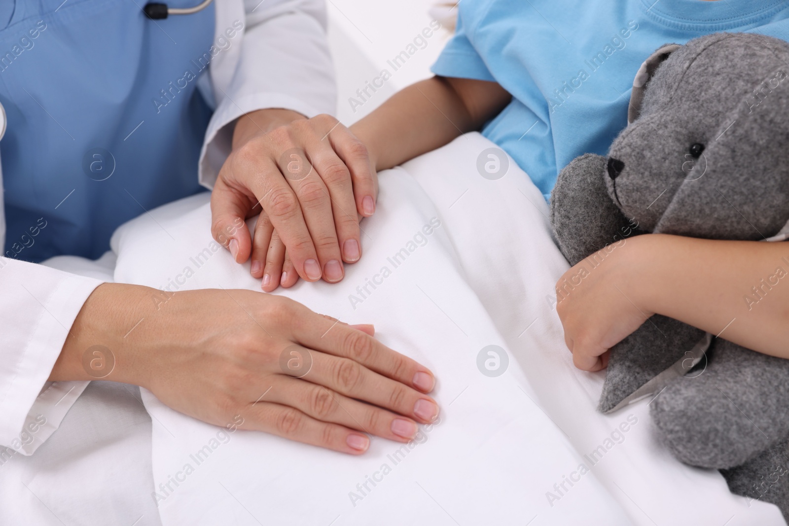 Photo of Doctor examining little girl on bed at hospital, closeup