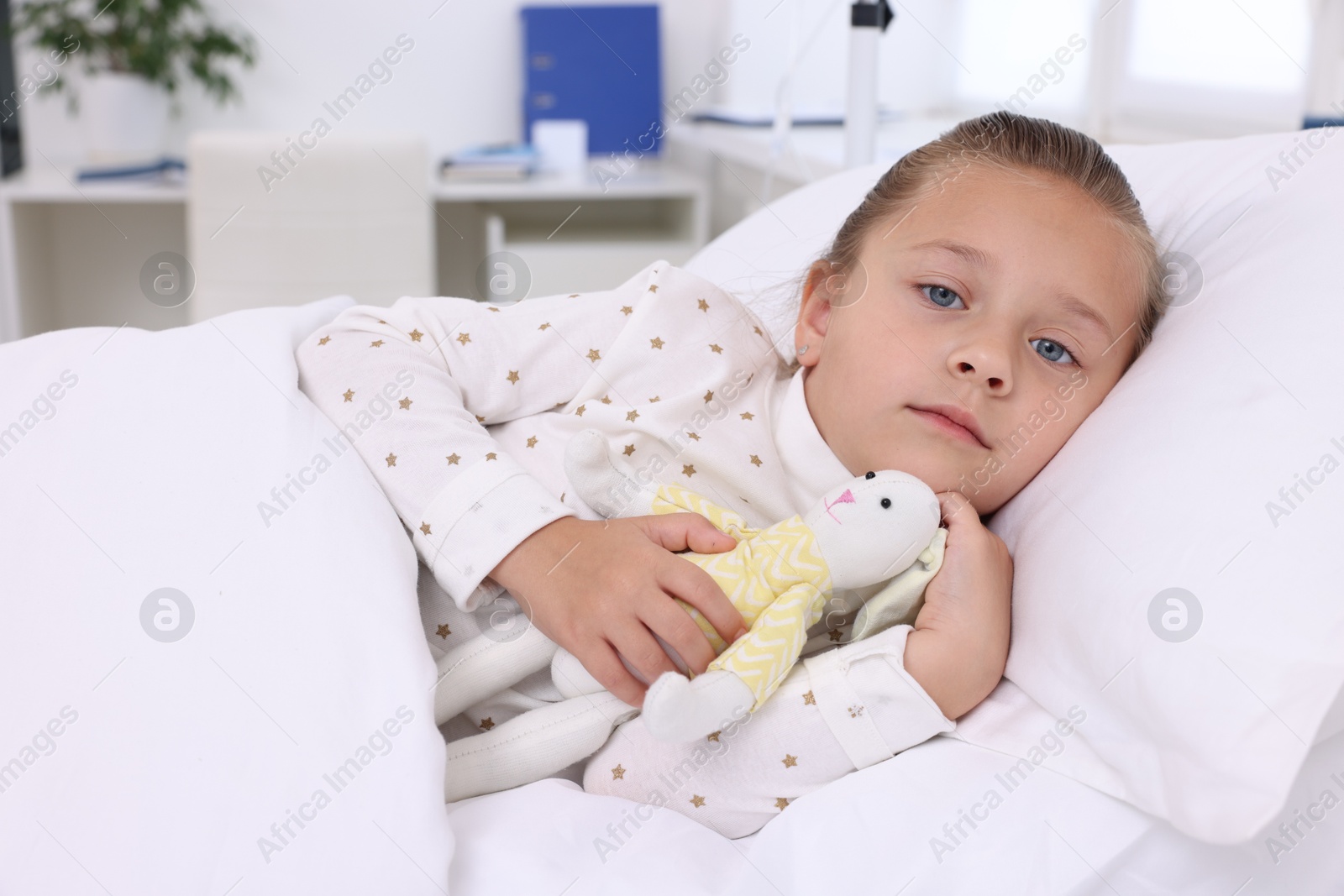 Photo of Cute little girl with toy bunny on bed in hospital