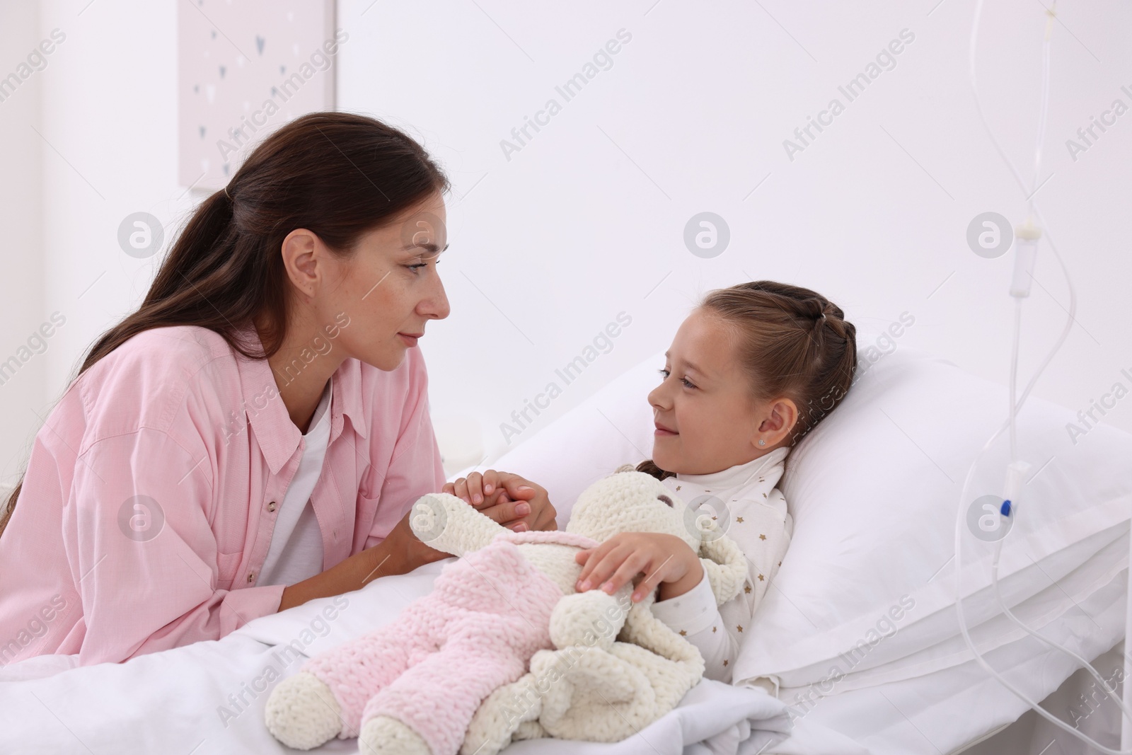 Photo of Mother and her little daughter on bed in hospital