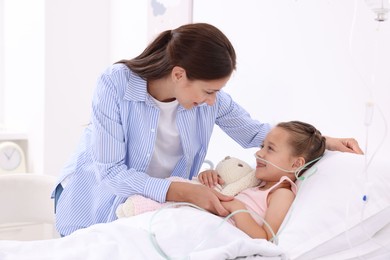 Mother and her little daughter on bed in hospital