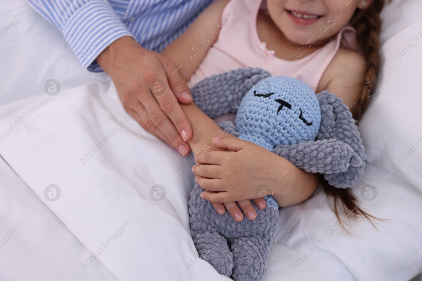 Photo of Mother and her little daughter on bed in hospital, closeup