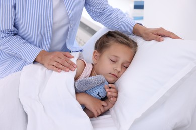 Photo of Mother and her little daughter on bed in hospital