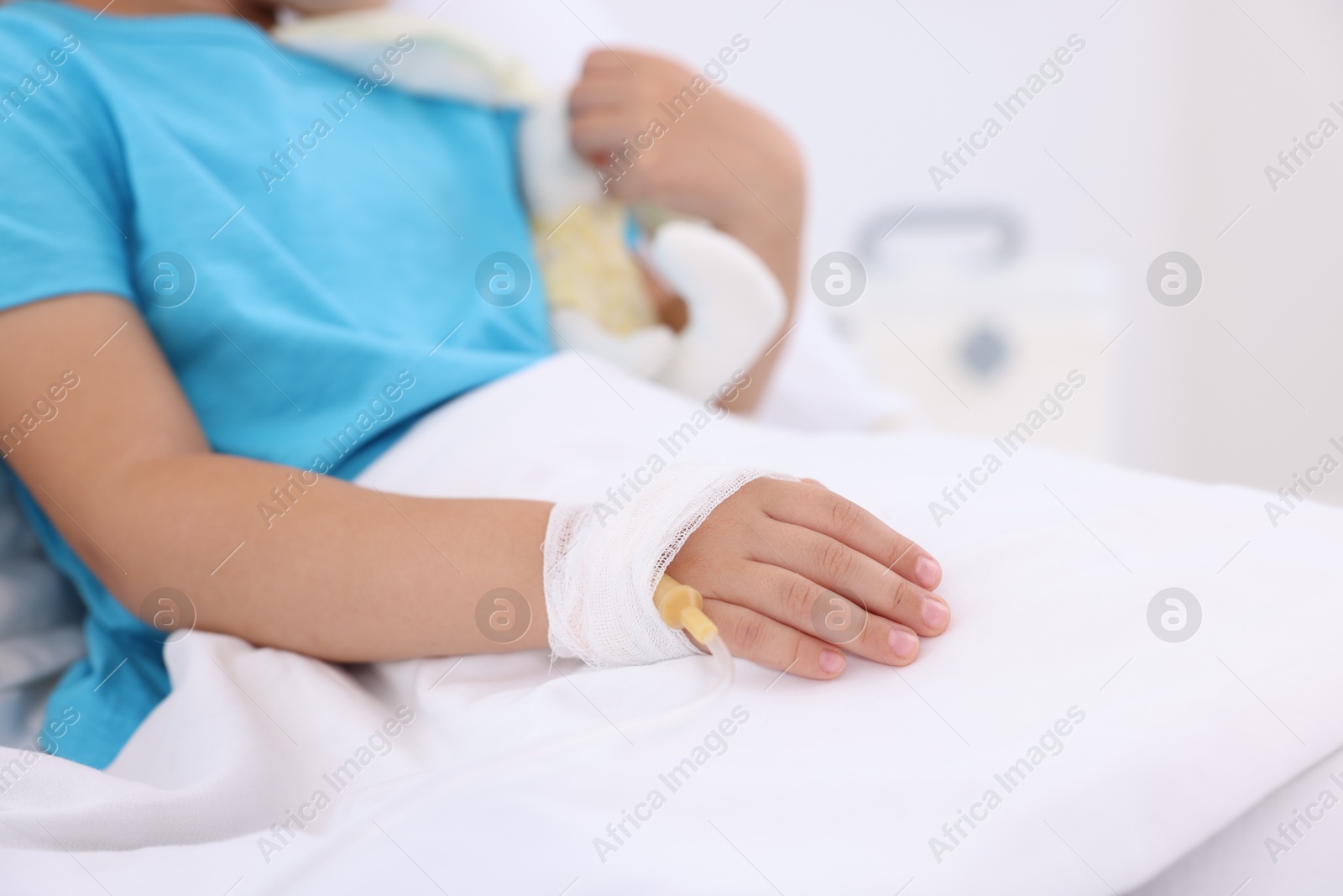 Photo of Little girl with IV drip on bed in hospital, closeup