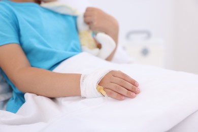 Little girl with IV drip on bed in hospital, closeup