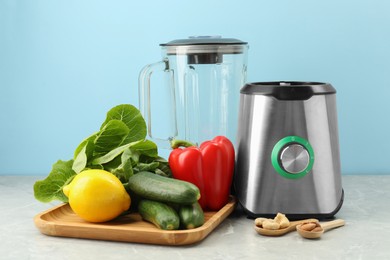 Blender and products on grey table against light blue background