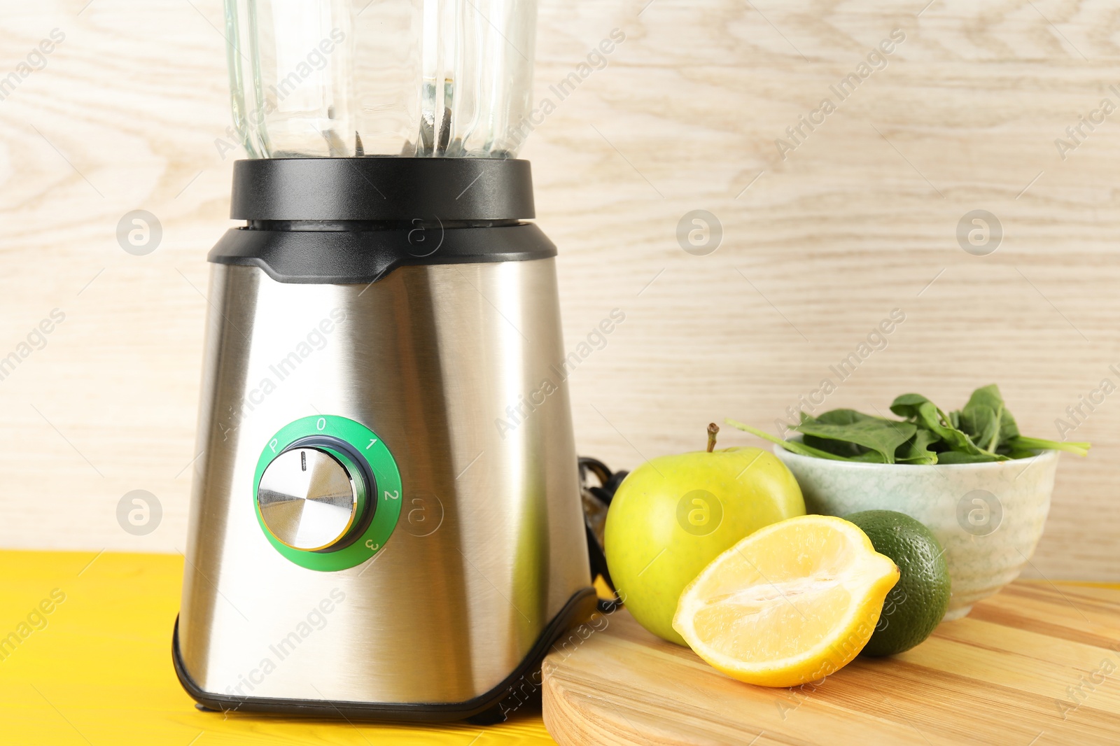 Photo of Modern blender with ingredients for smoothie on yellow wooden table