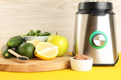 Photo of Modern blender with ingredients for smoothie on yellow wooden table, closeup