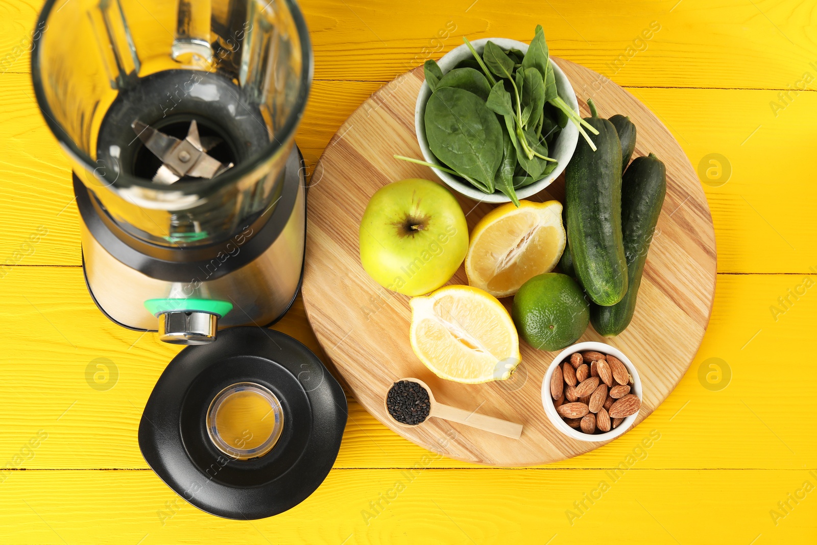 Photo of Modern blender with ingredients for smoothie on yellow wooden table, top view