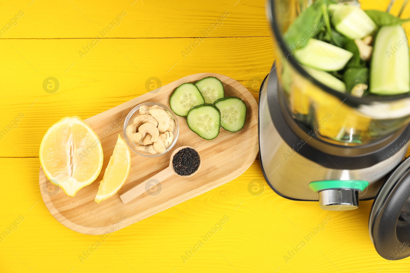 Photo of Modern blender with ingredients for smoothie on yellow wooden table