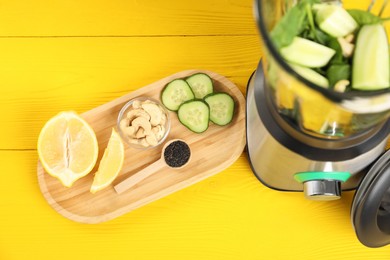 Photo of Modern blender with ingredients for smoothie on yellow wooden table