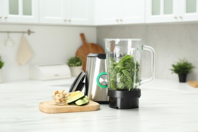 Modern blender with ingredients for smoothie on white marble table in kitchen