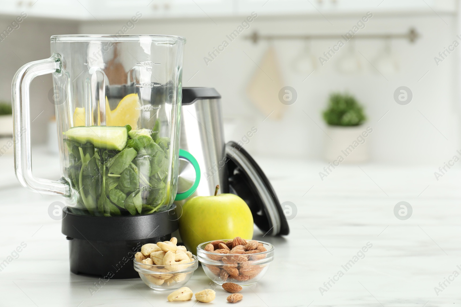 Photo of Modern blender with ingredients for smoothie on white marble table in kitchen. Space for text