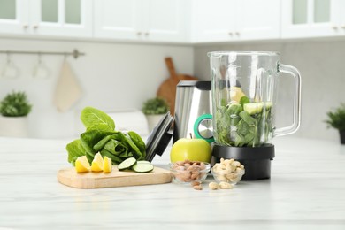 Photo of Modern blender with ingredients for smoothie on white marble table in kitchen