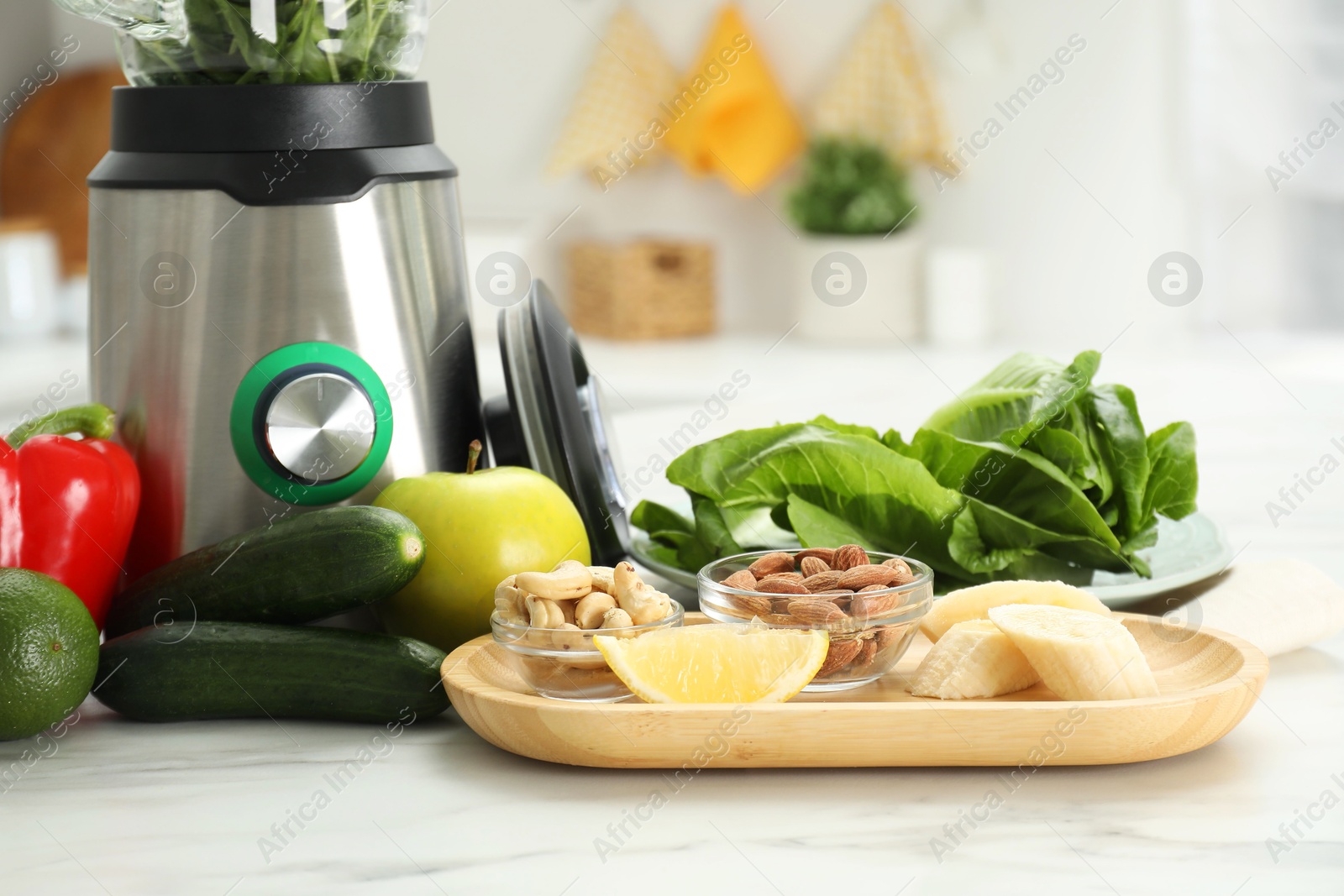 Photo of Modern blender with ingredients for smoothie on white marble table in kitchen, closeup