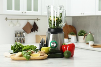 Photo of Modern blender with ingredients for smoothie on white marble table in kitchen