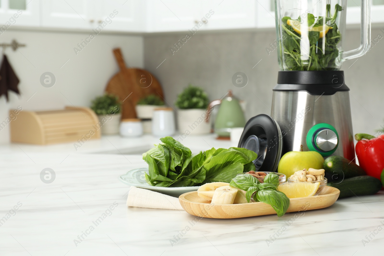 Photo of Modern blender with ingredients for smoothie on white marble table in kitchen. Space for text