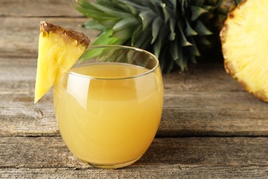 Photo of Tasty pineapple juice in glass and fresh fruit on wooden table, closeup