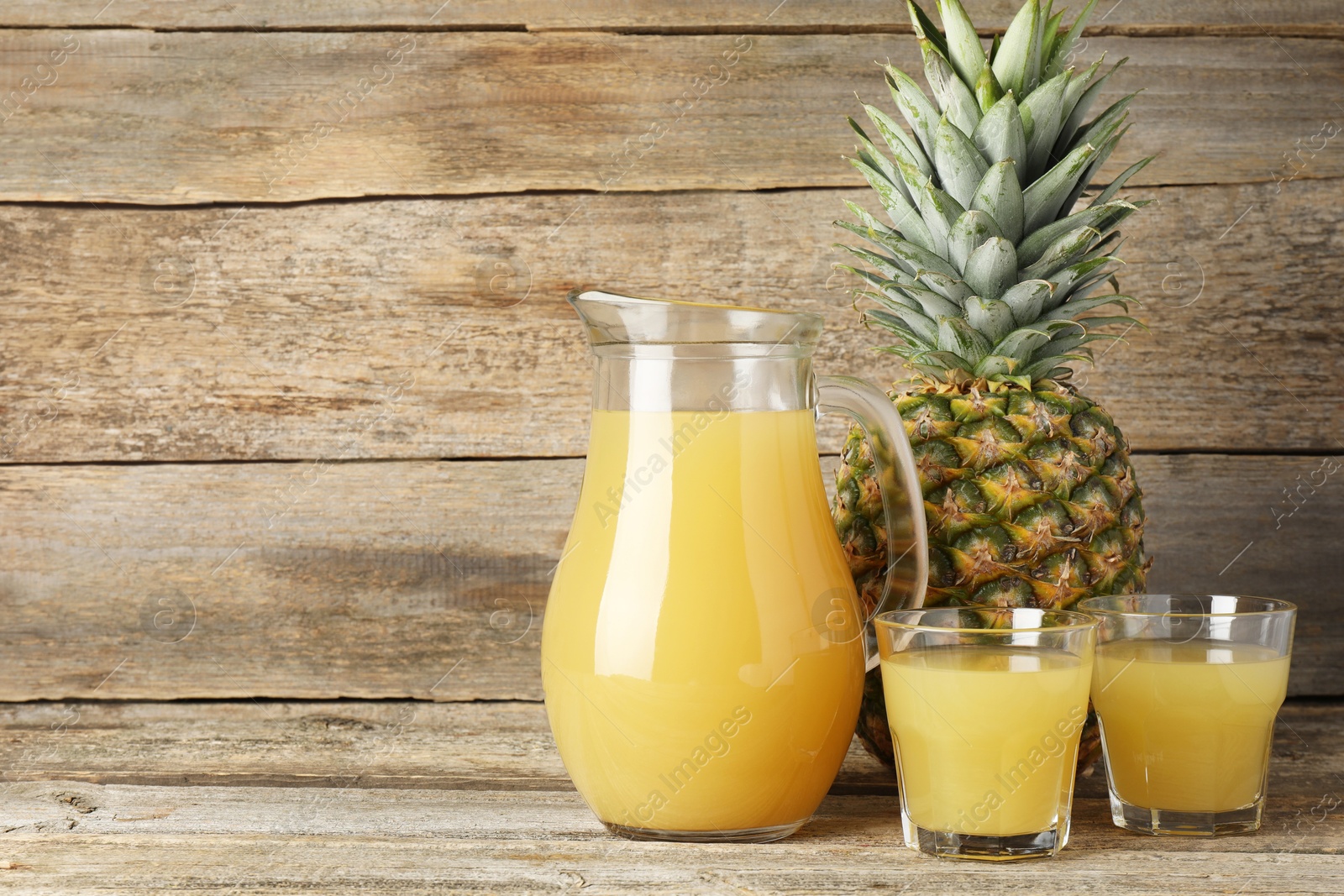 Photo of Tasty pineapple juice and fresh fruit on wooden table. Space for text