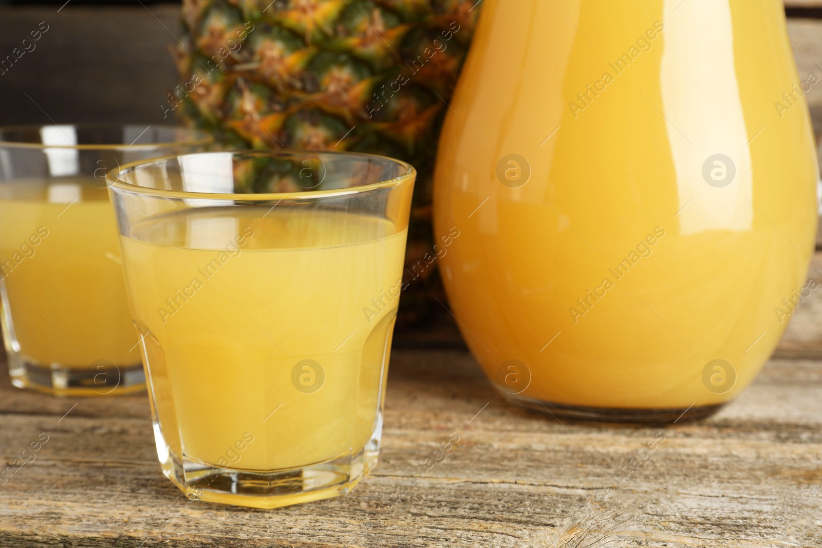 Photo of Tasty pineapple juice and fresh fruit on wooden table, closeup