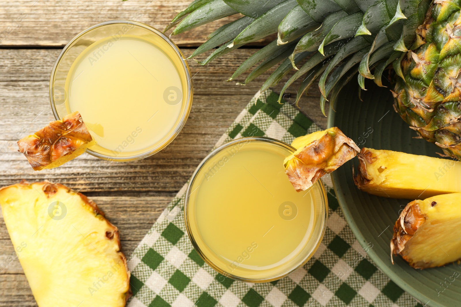 Photo of Tasty pineapple juice in glasses and fresh fruit on wooden table, flat lay