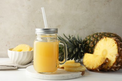 Photo of Tasty pineapple juice in mason jar and fresh fruits on white wooden table against grey background, closeup