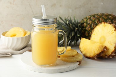 Photo of Tasty pineapple juice in mason jar and fresh fruits on white wooden table against grey background, closeup