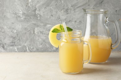 Photo of Tasty pineapple juice on grey textured table, closeup. Space for text