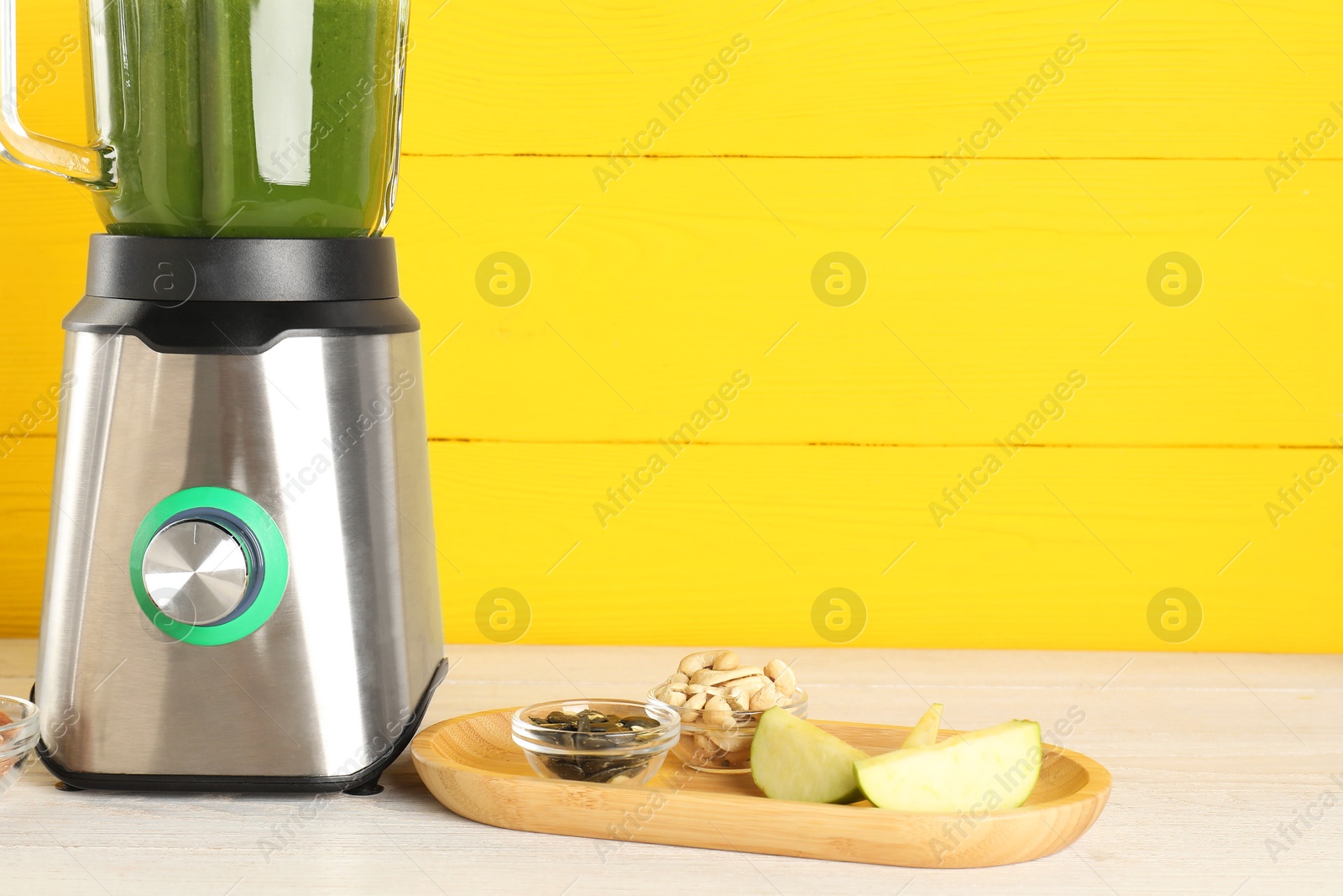 Photo of Modern blender with smoothie and ingredients on light wooden table. Space for text