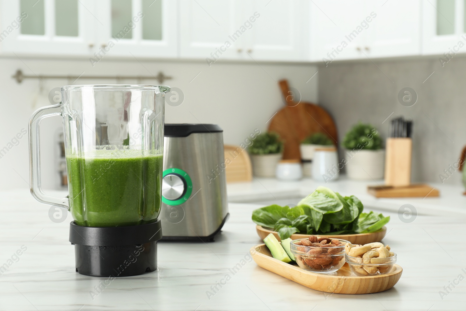 Photo of Modern blender with smoothie and ingredients on white marble table in kitchen