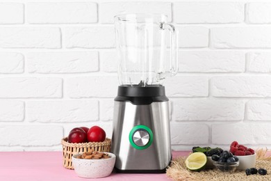 Photo of Blender and fresh ingredients on pink wooden table