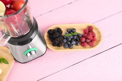 Photo of Blender and fresh ingredients on pink wooden table, above view