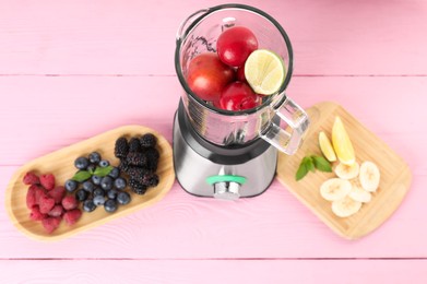 Photo of Blender and fresh ingredients on pink wooden table, above view