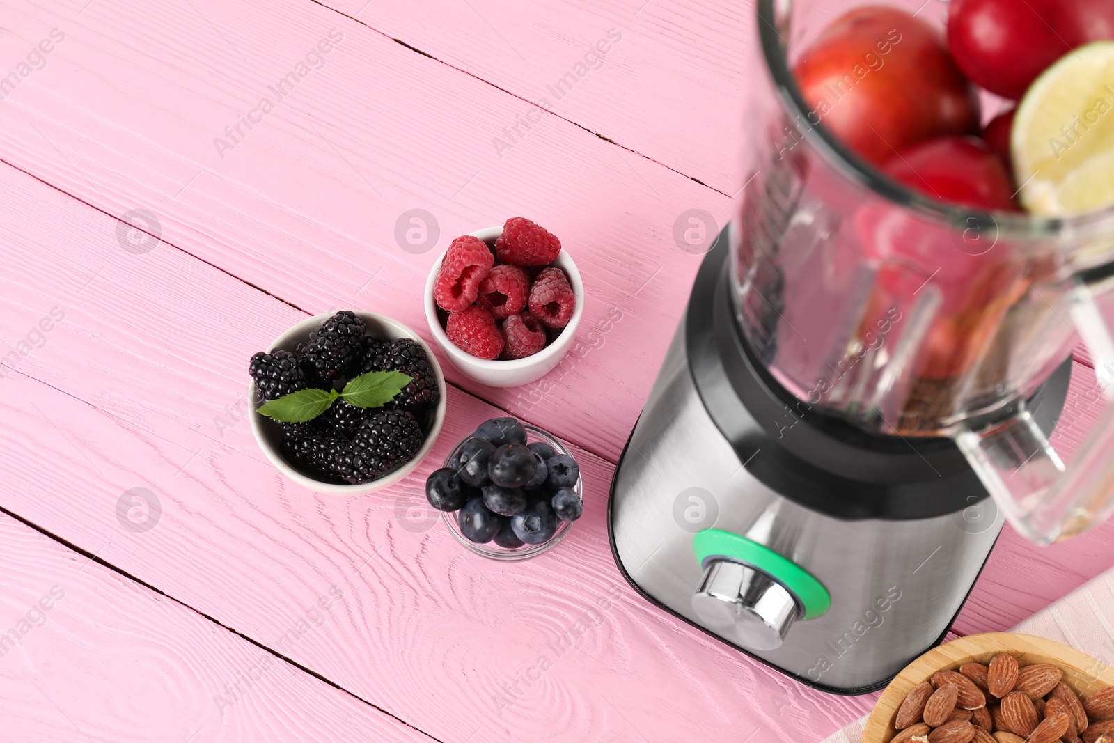 Photo of Blender and fresh ingredients on pink wooden table, above view