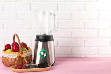 Photo of Blender and fresh ingredients on pink wooden table, space for text