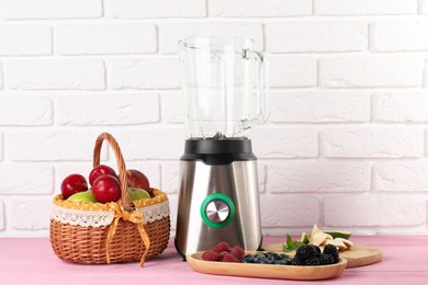 Photo of Blender and fresh ingredients on pink wooden table