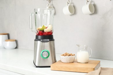 Blender and fresh ingredients on white countertop in kitchen