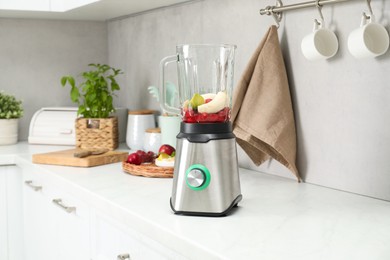 Blender and fresh ingredients on white countertop in kitchen