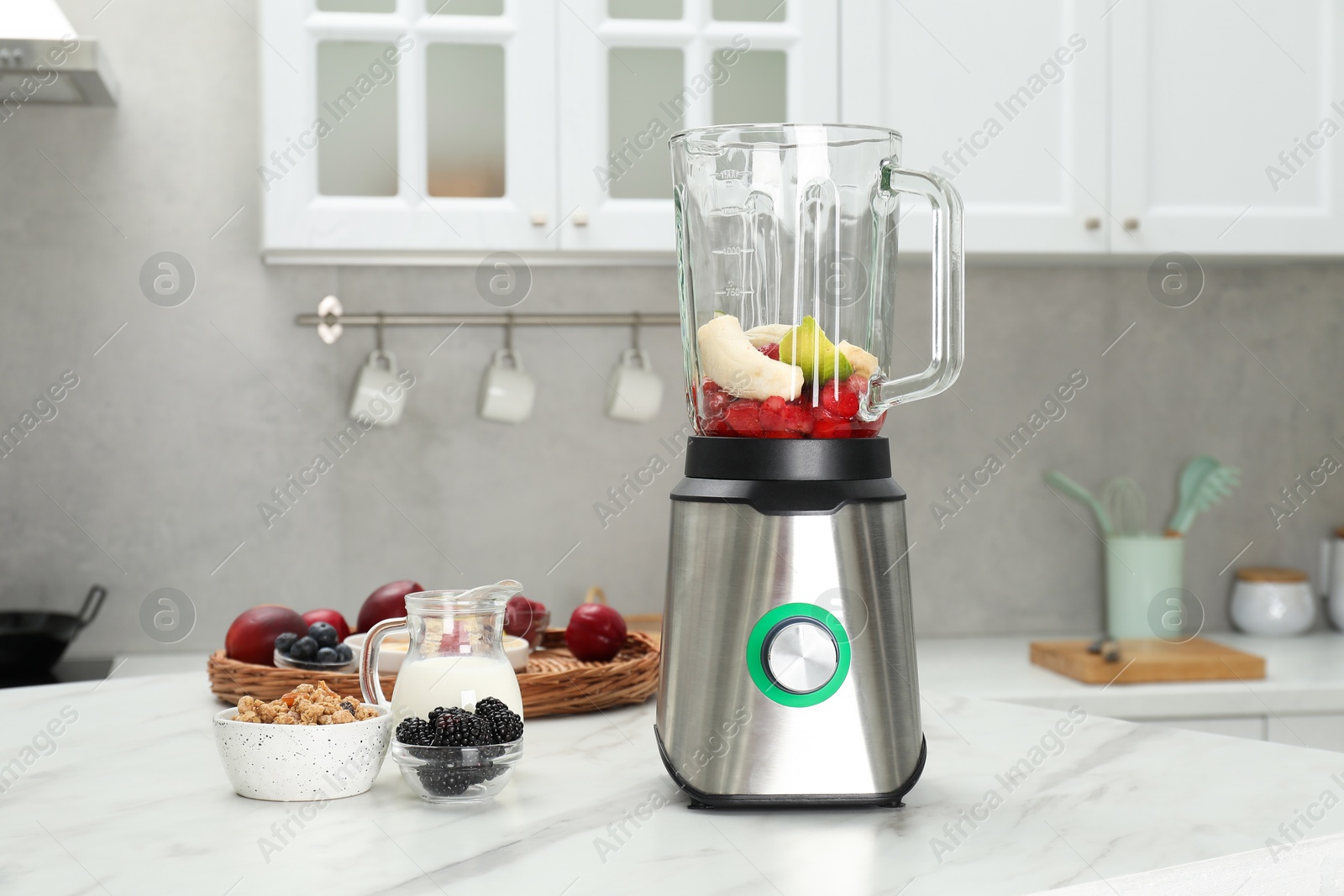 Photo of Blender and fresh ingredients on white marble table in kitchen