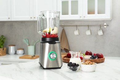 Photo of Blender and fresh ingredients on white marble table in kitchen