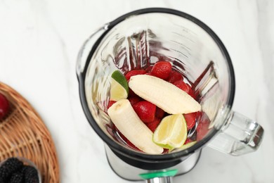 Photo of Blender and fresh ingredients on white marble table, above view