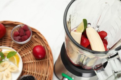 Photo of Blender and fresh ingredients on white table, closeup