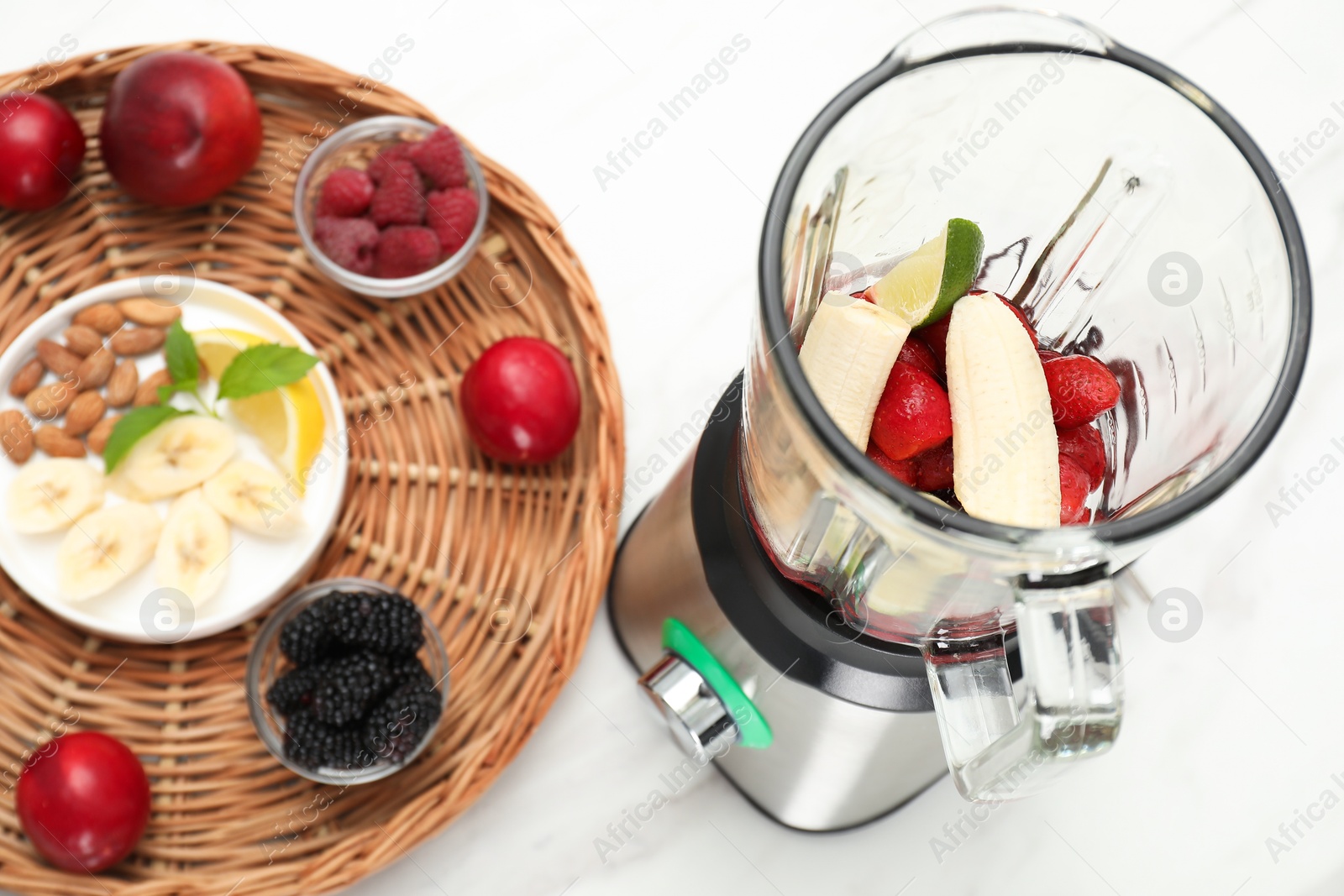 Photo of Blender and fresh ingredients on white table, closeup